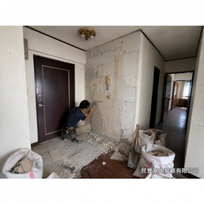 全室系統傢具裝修-師傅使用電動鑿除工具打除玄關舊磁磚，清理地面基底，為新磁磚鋪設做好準備，現場垃圾袋裝袋整齊，保持施工環境整潔有序
